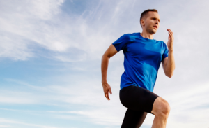 A man running, wearing a blue tshirt and black shorts.